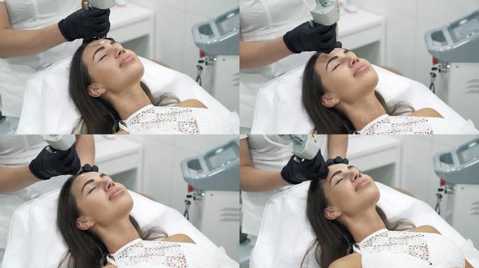 特写医生美容师在一件长袍和手套执行激光程序在一个女性病人的脸上。整形和扩张手术，门诊皮肤置换。无菌室