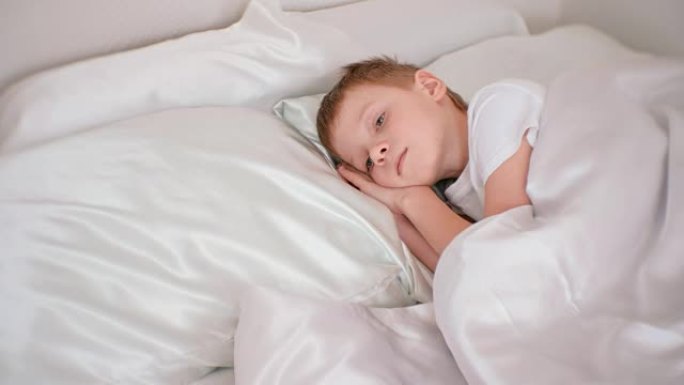 七岁的男孩静静地躺在房间的床上，双手放在头下。