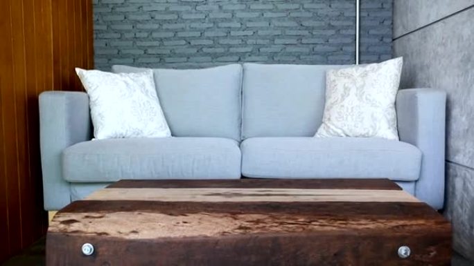 灰色沙发风格的阁楼在咖啡馆里有两个枕头。看起来优雅，非常优雅，有一个木制的栏杆桌子。