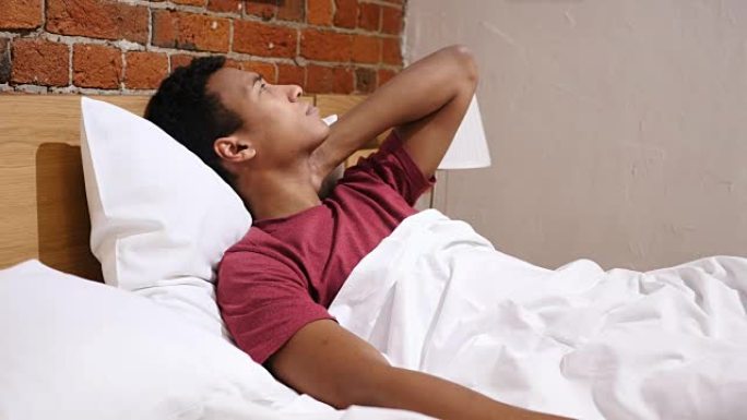 疲倦的非洲男人脖子疼痛，躺在床上放松