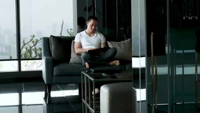 亚洲帅哥在家下班后在沙发上看书