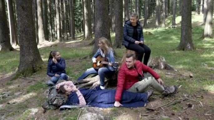 在树林里欢快的年轻露营者在弹吉他唱歌和自拍中玩耍