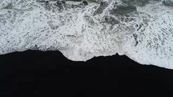 海浪冲向冰岛黑沙滩的航拍画面。