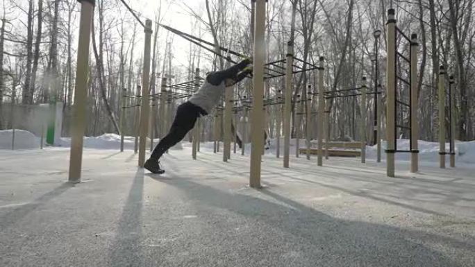 健身男子在冬季运动场用运动带锻炼。运动生活方式