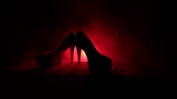 黑色麂皮高跟鞋女鞋，深色色调的雾状背景。特写。女性权力或女性统治概念。选择性聚焦。滑块镜头