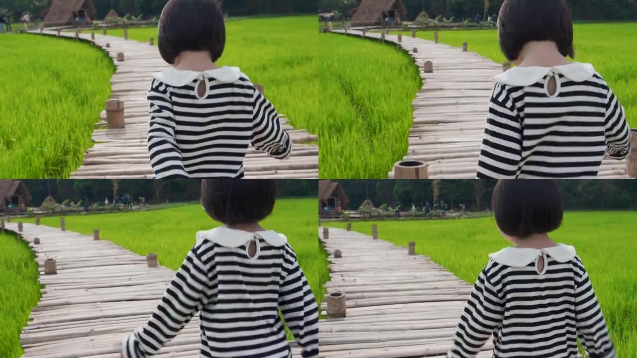 女孩的感觉享受和在稻田的木桥上行走