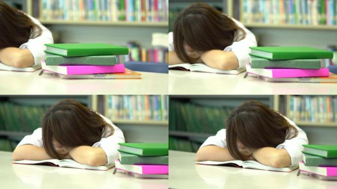 亚洲女学生在睡觉和醒来时在学校图书馆看书