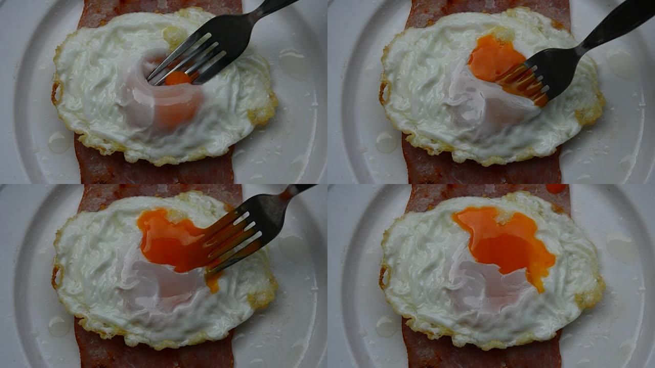 火腿煎蛋，叉子刺伤奶油蛋黄