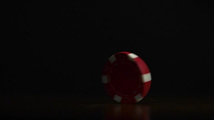 Cinemagraph-桌上扑克筹码的旋转隔离在黑色背景上。扑克筹码变淡。扑克筹码在桌子上旋转，孤立