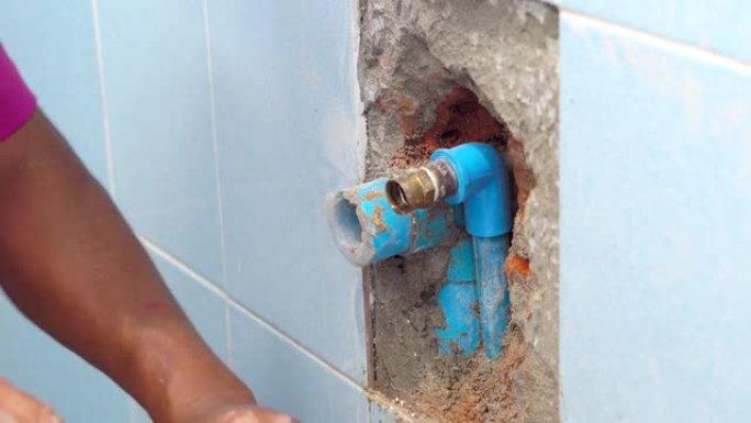 工人正在用浴室的供水管道在墙壁上抹灰