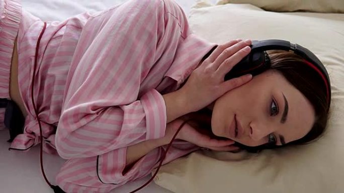 睡衣美女躺着戴着耳机听音乐