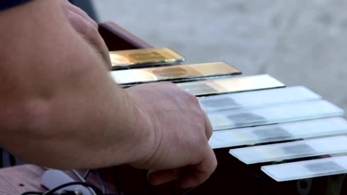 特写，音乐家的手从自己制作的玻璃竖琴中提取乐谱