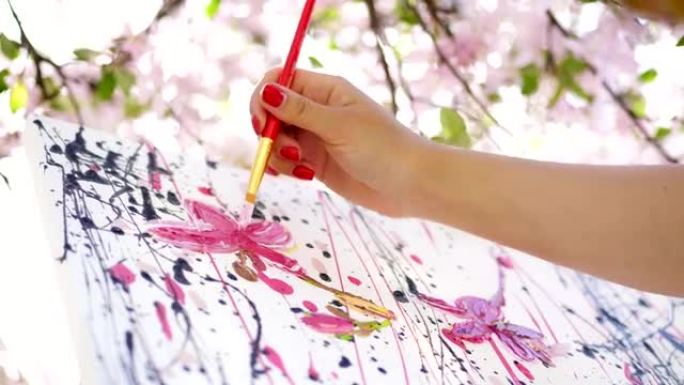 特写，女手，画家，艺术家在盛开的春天苹果园里画了一幅花，她用画笔将油画颜料涂在画布上，创作过程