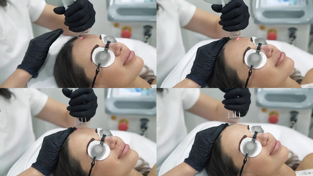 医生美容师穿着晨衣和手套在女性病人的脸上执行激光程序特写。整形和扩张手术，门诊皮肤置换。无菌室里的医