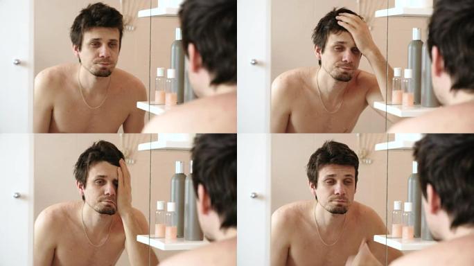 疲倦的男人刚刚醒来，看着镜子里的倒影，用手拉直头发