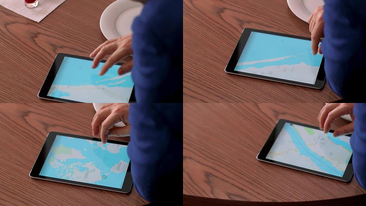 男性手触摸屏平板电脑，用于在木桌背景上浏览世界地图