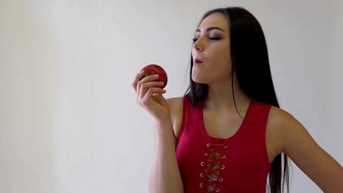 美丽的黑发女孩吃白色的红苹果