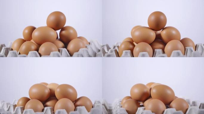 鸡蛋堆叠在纸板盘中的金字塔中，手拿一个鸡蛋