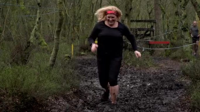 在泥泞中竞争的妇女穿过林地-慢动作