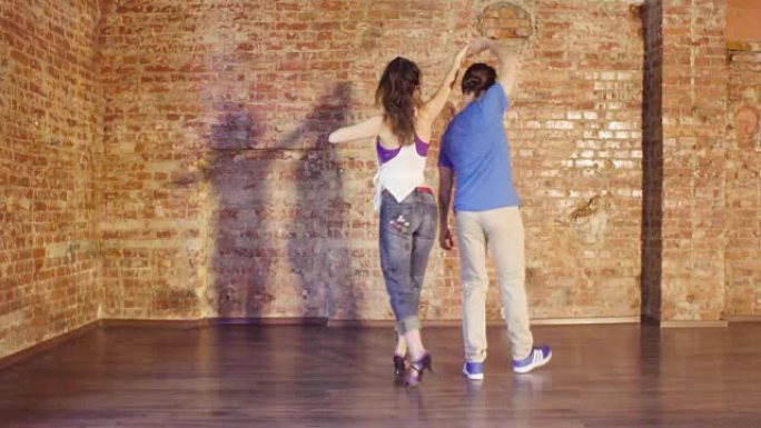 夫妇在大厅里用旧砖墙跳舞