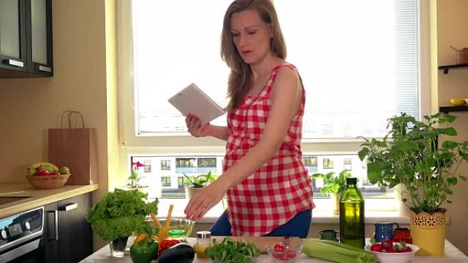 幸福孕妇用平板电脑电脑在家准备蔬菜沙拉