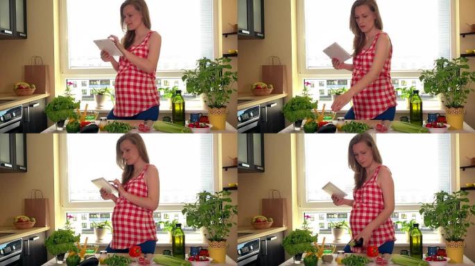 幸福孕妇用平板电脑电脑在家准备蔬菜沙拉