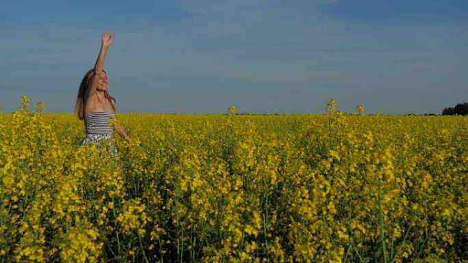 快乐的女孩跑过黄花的田野，挥手欢迎。