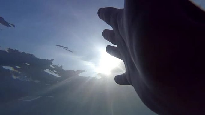 盖伊溺水在海洋或海洋中漂浮到水面的观点。雄性的手从水下伸展到阳光。手臂寻求帮助，并试图到达太阳。特写