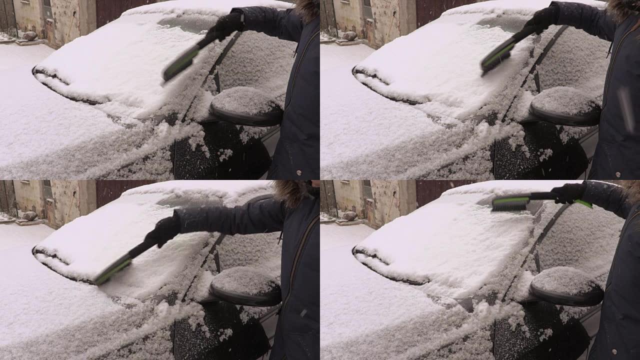 下雪天汽车附近有刷子的女人