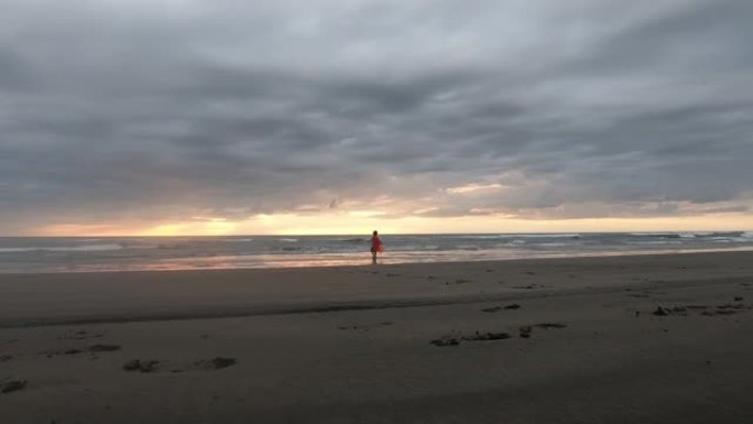 日落时在新西兰Murawai海滩上玩耍的小男孩超级英雄