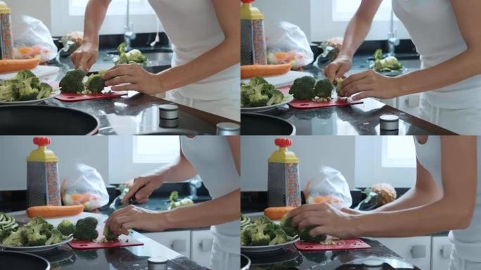 年轻女子在家庭厨房切花椰菜。