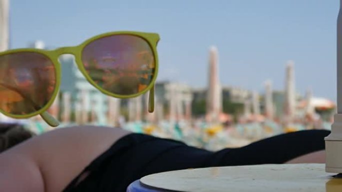在令人惊叹的日落期间，太阳镜躺在热带海滩的木桌上。旅游度假概念。慢动作。泰国。1920x1080