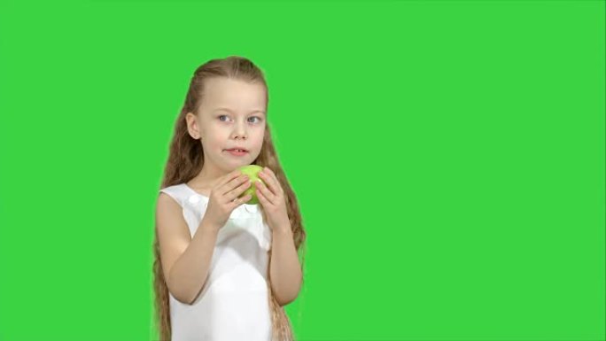 一个小女孩在绿屏上吃青苹果的肖像，色键