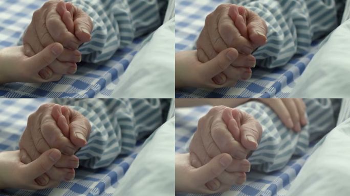 年轻人的手紧握老人病人的手