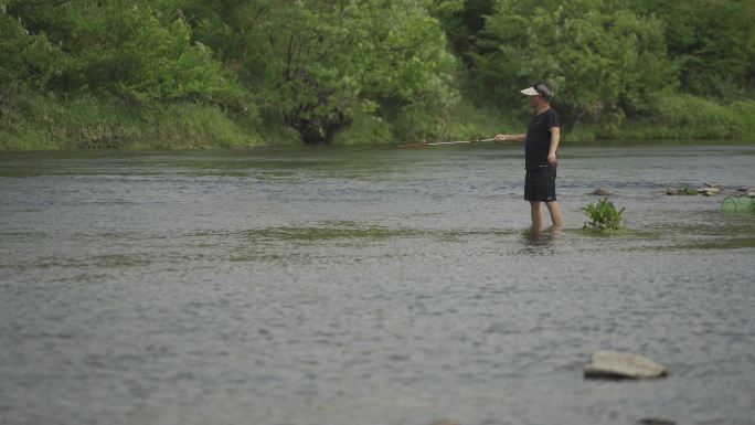站在河里钓鱼的人