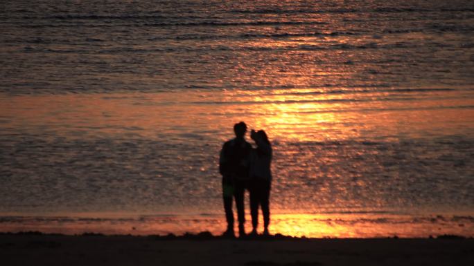 威海西海岸小石岛沙滩上看落日的情侣