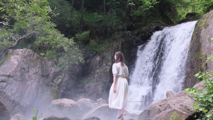 美女在山野瀑布溪水前驻足