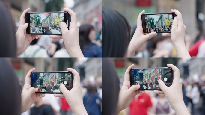 游客在步行街拿手机拍照记录生活