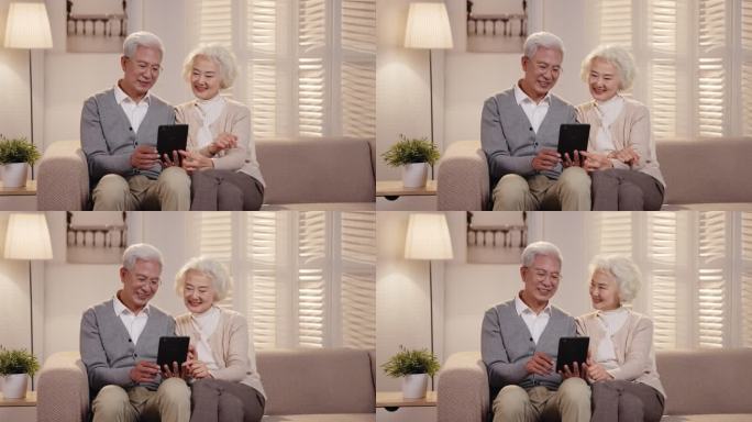 老年夫妇坐在沙发上看平板电脑