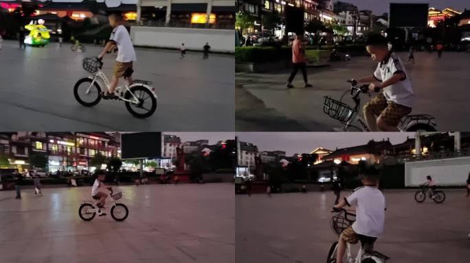 夜晚骑自行车的小男孩小孩在闹市区骑踩单车