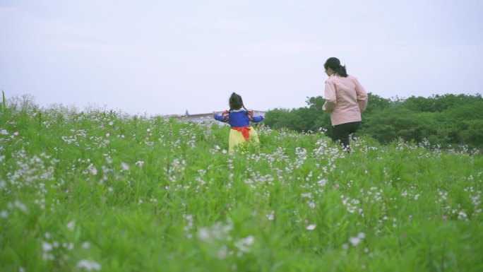 母亲牵小孩大手拉小手漫步在田野陪伴孩子