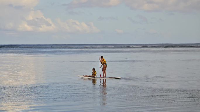 清晨一对母女在平静的海面上划桨板