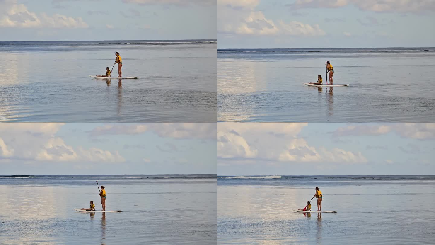 清晨一对母女在平静的海面上划桨板