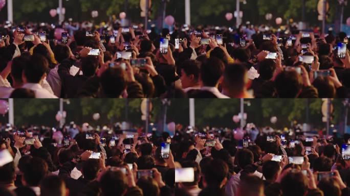 拿手机观看手机拍照自拍繁华市中心夜景人群