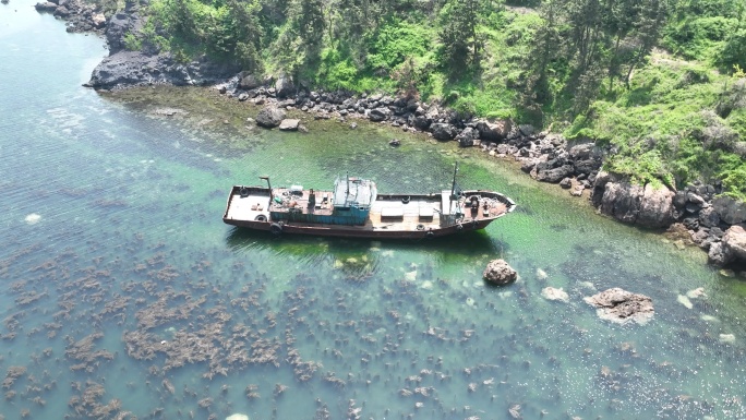 航拍俯瞰夏季海岸边搁浅的一条荣成渔船