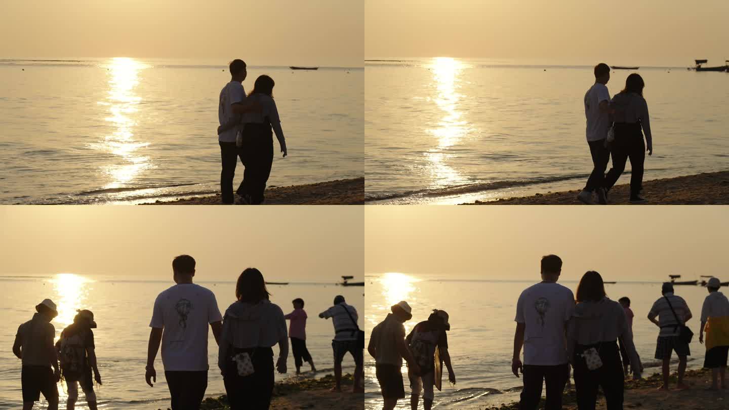 唯美海边日出日落散步的情侣游客