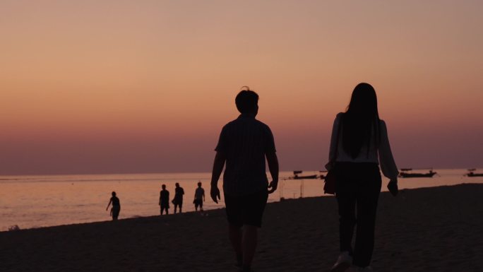 唯美海边日出日落散步的夫妻情侣游客