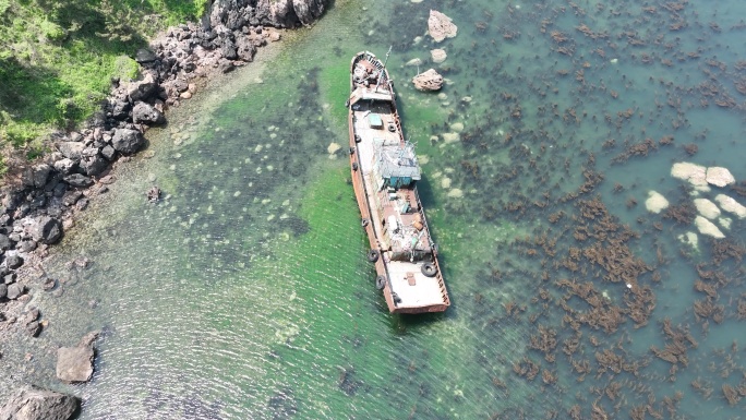 航拍俯瞰夏季海岸边搁浅的一条荣成渔船