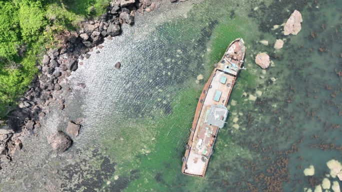 航拍俯瞰夏季海岸边搁浅的一条荣成渔船