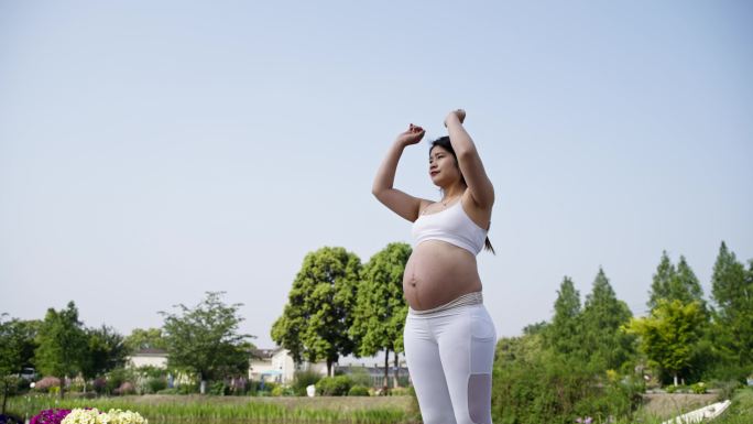 准妈妈孕妇在花园抚摸大肚子展开双臂